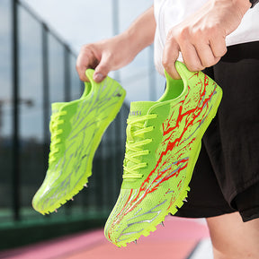 Person holding bright green running shoes with red accents on a blurred outdoor background
