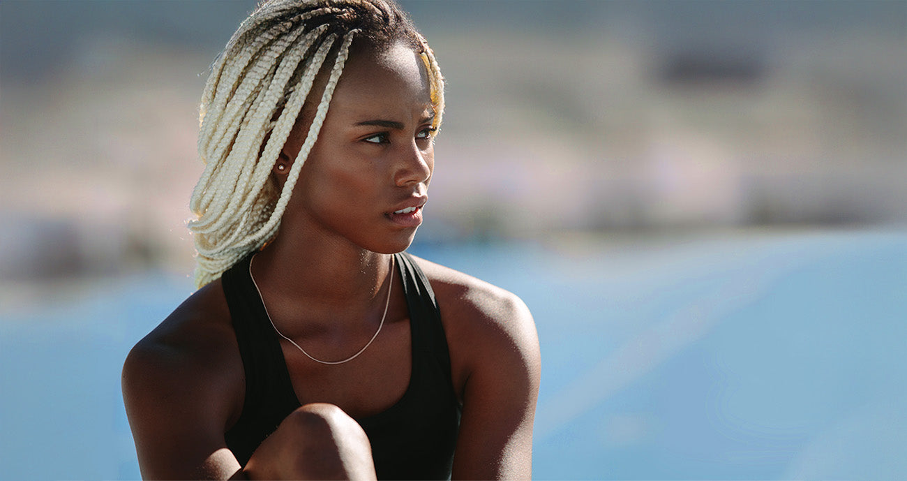 black girl sitting on blue running track