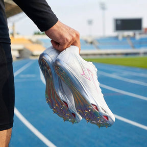 Person holding a white running shoe with spikes on a track field